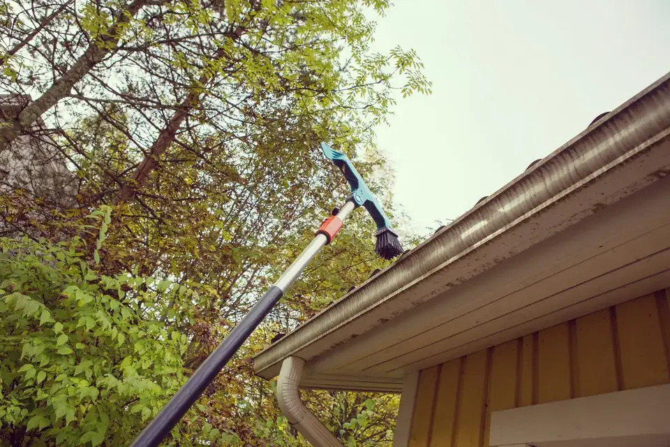 Gutter being cleaned with an extension pole